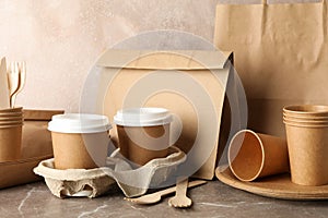 Eco - friendly tableware and paper bag on grey table