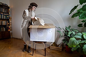 Eco-friendly teen girl packing old organic cotton clothes in cardboard box for recycling, reuse