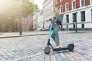 eco friendly transport - young business woman rides electric scooter in the city streets