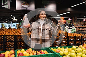 Eco friendly woman buys apples in the supermarket. Female grocery shopper opposes the use of plastic bags.