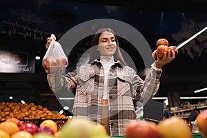 Eco friendly woman buys apples in the supermarket. Female grocery shopper opposes the use of plastic bags.
