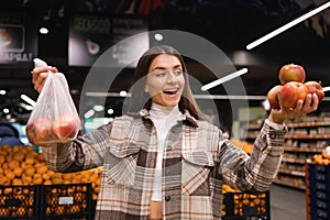 Eco friendly woman buys apples in the supermarket. Female grocery shopper opposes the use of plastic bags.