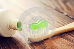 Eco friendly wooden bamboo toothbrush with toothpaste and tube of toothpaste closeup