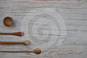Eco-friendly wooden bowl, spoons and honey stick on wooden table background. Environmentally friendly kitchen utensil flat lay