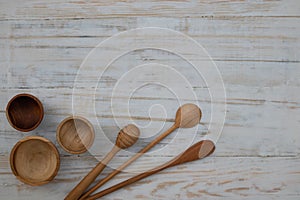 Eco-friendly wooden bowls, spoons and honey stick on wooden table background. Environmentally friendly kitchen utensil flat lay