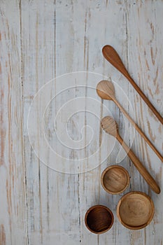 Eco-friendly wooden bowls, spoons and honey stick on wooden table background. Environmentally friendly tableware flat lay with