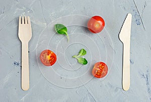 Eco-friendly wooden knife and fork on gray background. Abstract food background with wooden cutlery. Top view with copy space.