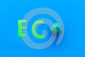 Eco icon cutout near planet Earth plastiline symbol on blue background top view copy space