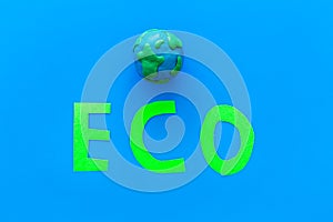 Eco icon cutout near planet Earth plastiline symbol on blue background top view copy space