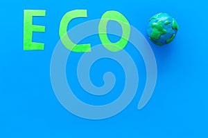 Eco icon cutout near planet Earth plastiline symbol on blue background top view space for text