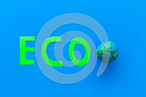 Eco icon cutout near planet Earth plastiline symbol on blue background top view space for text
