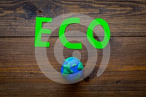 Eco icon cutout near planet Earth plastiline symbol on dark wooden background top view copy space