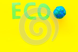 Eco icon cutout near planet Earth plastiline symbol on yellow background top view copy space