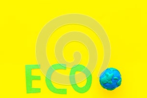 Eco icon cutout near planet Earth plastiline symbol on yellow background top view copy space