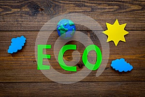 Eco icon cutout near plastiline symbol of planet Earth on dark wooden background top view