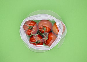 ECO-natural bags with fruits and vegetables, red tomatoes on a light green background
