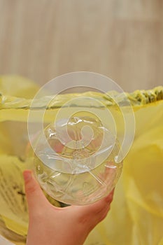 Eco plastic. bottles in a yellow plastic bag. Collecting bottles for recycling. hand throws bottle into a trash bag