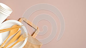 Eco store banner design template. Empty kraft paper bag and eco-friendly cutlery set on brown background. Flat lay, top view.