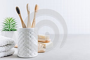 Eco toothbrushes. Bamboo toothbrushes cup, natural soap, wooden hair brush and white towels on gray stone background
