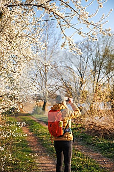 Eco tourism. Woman hiker with binoculars observes birds arriving at lake in spring