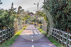 Eco view pedestrian / cycle lane, with cyclist pedaling and agricultural fields, trees and house as background