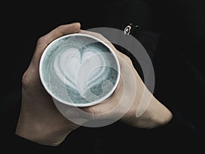 Ecofriendly cup of fresh trendy blue matcha latte in woman hands. Classic latte art. Empty place for text, copy space. Coffee