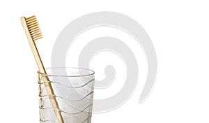 Ecological bamboo toothbrush in a glass cup on a white background