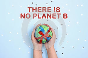 Ecological concept with globe in hands on blue background and text. There is no planet B.