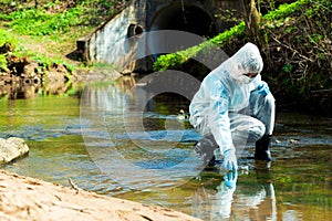 ecological disaster, contaminated water comes out of the sewage system - an ecologist takes a sample of water photo
