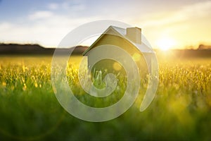 Ecological green wood  model house in empty field at sunset