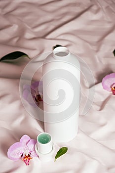 Ecological laundry detergent among orchid flowers on bed linen