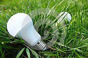 Ecological white led light bulb isolated in green grass close-up.