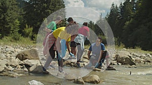 Ecologically aware diverse multiethnic people doing environmental cleanup on mountain river