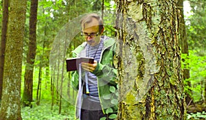 The ecologist in a forest writing in notebook.