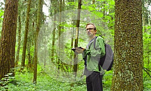 The ecologist in a forest writing in notebook.