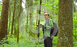 The ecologist in a forest writing in notebook. photo