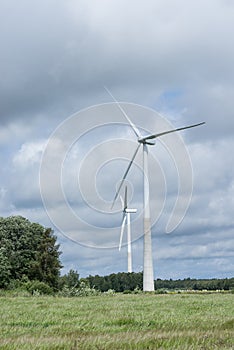 Ecology concept: Blue sky, white clouds, wind turbine and crop field. Wind generator for electricity, alternative energy source.