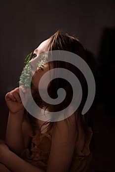 Ecology concept, pensive little girl with fern sprigs pasted with plasters on her cheeks