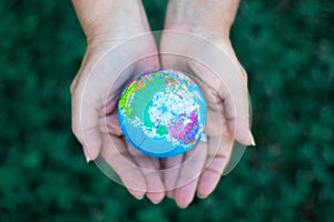 Ecology. Environmentally friendly planet.Woman holding planet model on green background, earth day concept