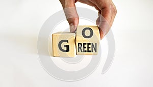 Ecology and go green symbol. Businessman turns a wooden cube with concept words `Go green` on a beautiful white table, white