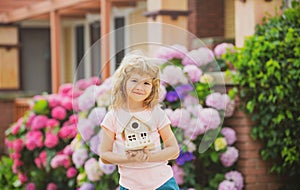 Ecology house in childrens hands against backyard. Happy dream home.