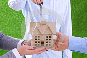 Ecology house and key in hands against green spring background