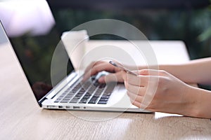 Ecommerce concept, Woman using credit card with ecommerce website via laptop on wooden desk