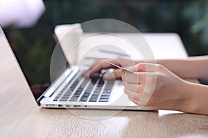 Ecommerce concept, Woman using credit card with ecommerce website via laptop on wooden desk