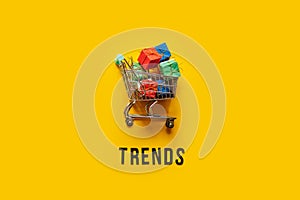 Ecommerce Retail Shopping trends concept. Word Trends and mini shopping cart with box on yellow background.