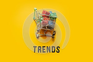 Ecommerce Retail Shopping trends concept. Word Trends and mini shopping cart with box on yellow background.