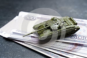 Economic crisis in Russia concept. Toy military tank on Russian rubles. War conflict in Ukraine, economic sanctions and