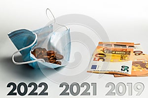 The economic effect of the pandemic between 2019 and 2022 - A protective mask filled with cents next to 50 euro banknotes, concept