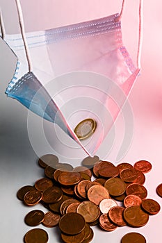 The economic effect of the pandemic - A protective mask filled with 1 euro coin hanging over euro cents leftover, concept