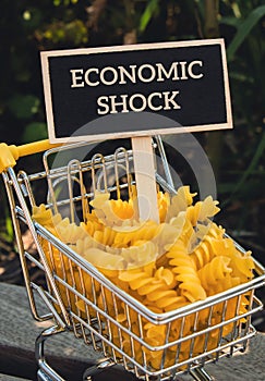 ECONOMIC SHOCK text on Blackboard label Shopping trolley cart Filled With Pasta on agriculture background. Food and